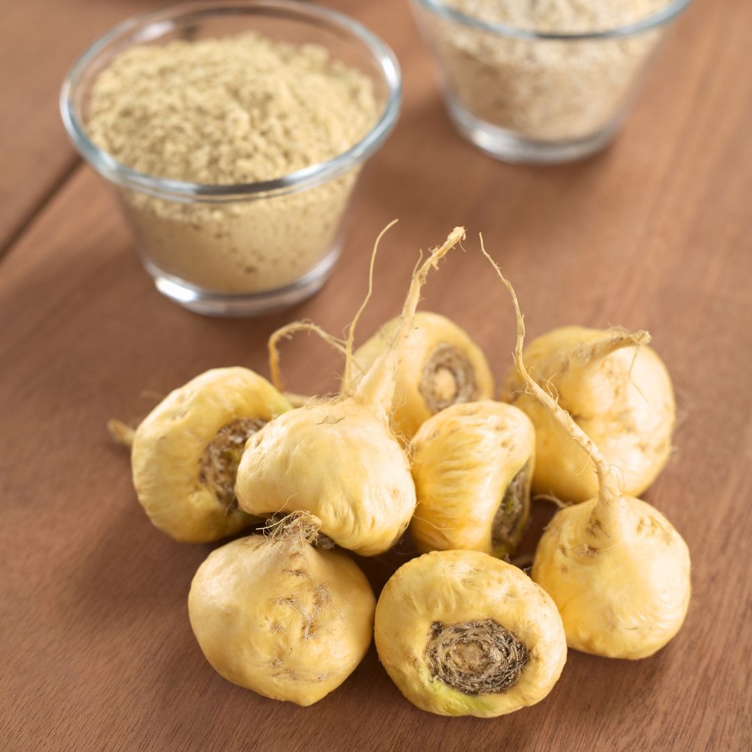 Golden maca roots and powder on a wooden table, representing its energy-boosting adaptogenic properties and nutty, earthy flavor.