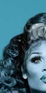 Stylized teal-toned close-up of Miss Peppermint with curled hair, stud earring, and dramatic lashes, gazing upward to the right; only half the face is visible.